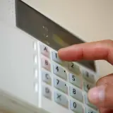 Dłoń naciska klawisz "1" na klawiaturze alarmu domowego.