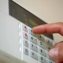 Dłoń naciska klawisz "1" na klawiaturze alarmu domowego.