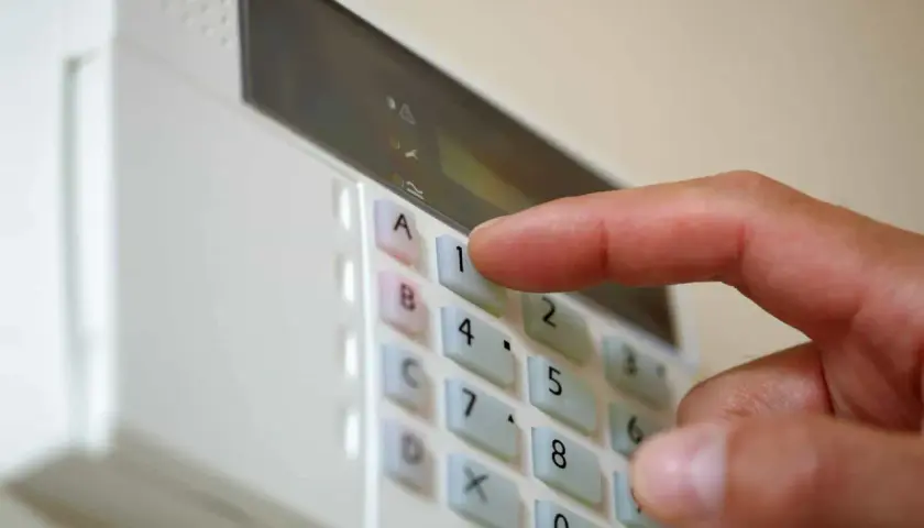 Dłoń naciska klawisz "1" na klawiaturze alarmu domowego.